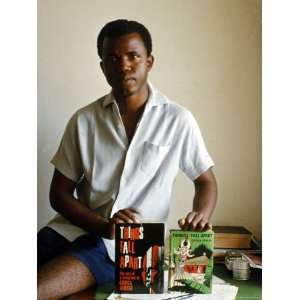 Nigerian Author Chinua Achebe Holding Two Editions of His Book Things 