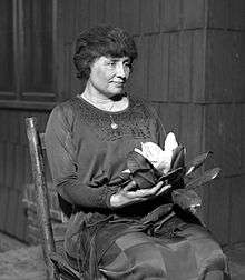 Helen Keller sitting holding a magnolia flower, circa 1920.